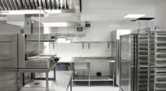 Professional commercial kitchen with stainless steel equipment and storage