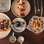 Overhead view of pizza, fries and a plated dish on a wooden restaurant table in Delhi