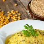 Yellow rice-and-lentil dish on a white plate beside uncooked rice and pulses