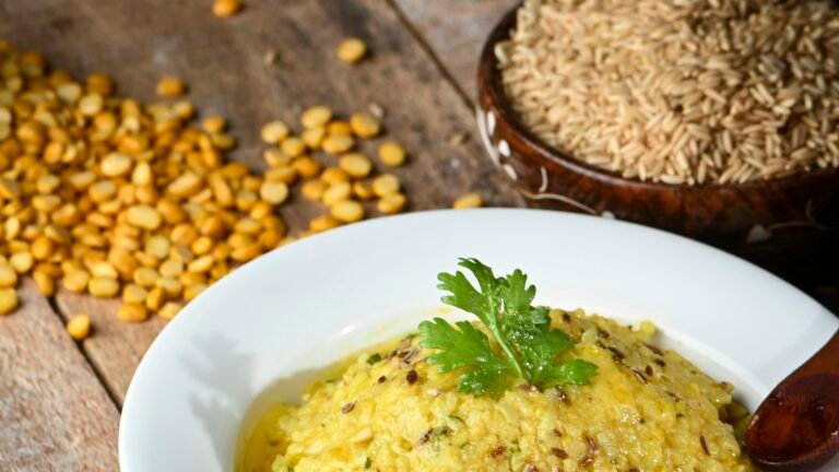 Yellow rice-and-lentil dish on a white plate beside uncooked rice and pulses