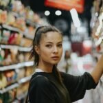 Shopper selecting packaged food from a grocery shelf; illustrative photograph, no FSSAI endorsement shown