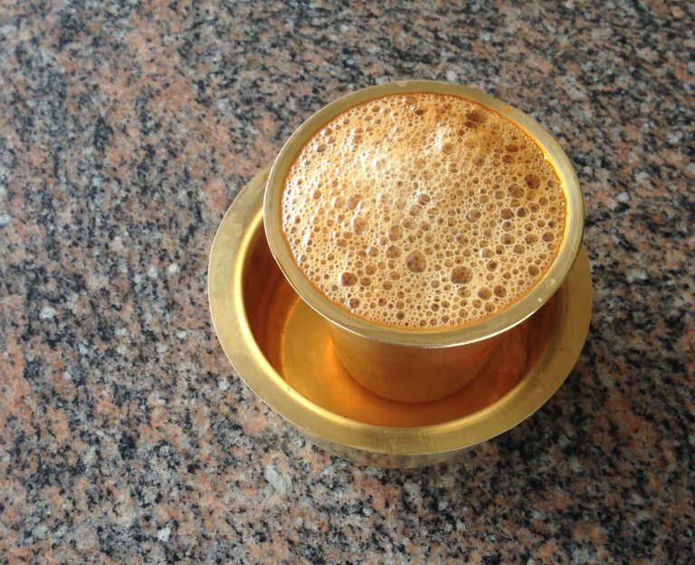 Frothy South Indian filter coffee in a metal tumbler and dabarah